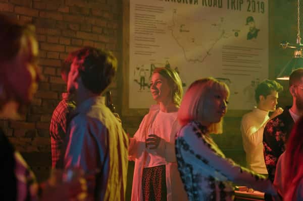 People socializing in a dim bar with brick walls and a large map on the back wall.