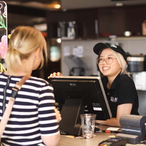 Friendly barista taking an order at the café counter inside The Spoke café, kitchen, and bar.