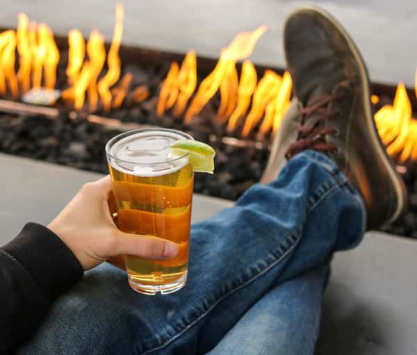 person holding beer by the fire