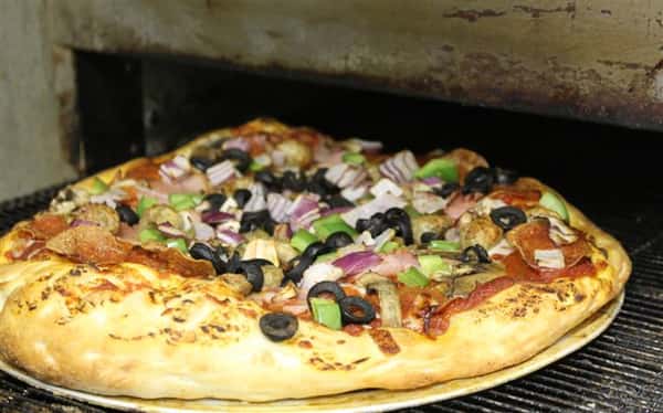vegetable pizza being taking out of an oven