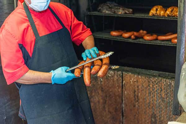 Staff removing sausage from grill
