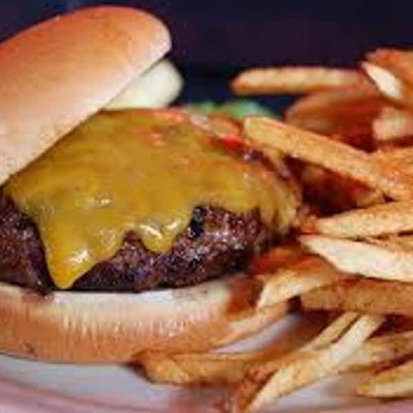 Cheeseburger with melted cheddar on a toasted bun, served with a generous portion of golden, crispy French fries.