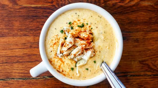 Creamy crab soup topped with crab meat, paprika, and chives in a white bowl.