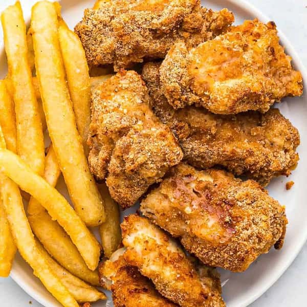 Crispy fried chicken tenders served with thick-cut French fries on a white plate.