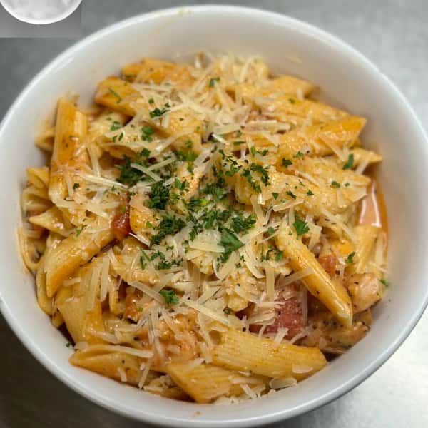 Penne pasta in a creamy tomato sauce, topped with shredded parmesan cheese and garnished with chopped parsley.