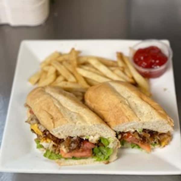 Toasted sub sandwich with lettuce, tomato, cheese, and ground meat, served with crispy fries and a side of ketchup.