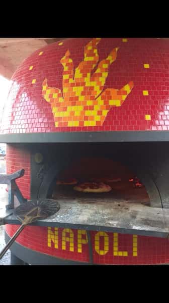 Outdoor wood burning pizza oven with pizza's cooking inside