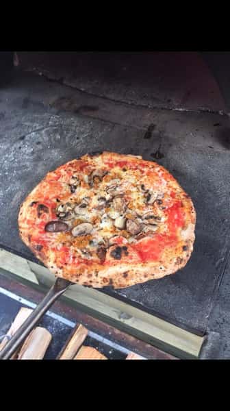 Outdoor wood burning pizza oven with pizza's cooking inside
