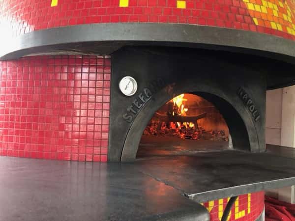 Outdoor wood burning pizza oven with pizza's cooking inside