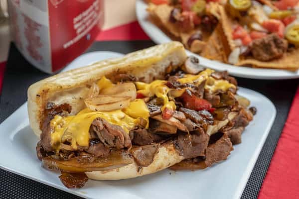 Mounds of Sliced Beef or Marinated Chicken Tenders with Grilled Onions, Mushrooms, Mixed Peppers and American Cheese on a Warm Hoagie