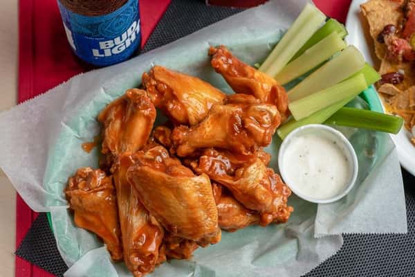 Chicken wings covered in buffalo sauce with a side of celery