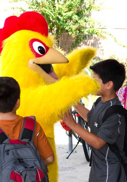 Chicken mascot hugging students