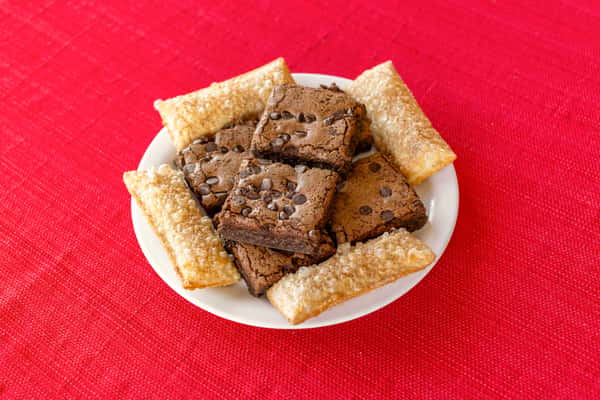 Dessert plate featuring rich chocolate chip brownies and golden, sugar-dusted fried pastries, arranged on a white dish over a bright red tablecloth, ideal for a Southern comfort food finish