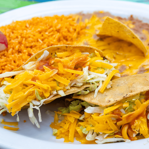 Crispy tacos filled with shredded lettuce, cheddar cheese, and salsa, served with Mexican rice and refried beans.