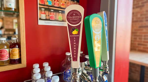 White kombucha tap handle for Elderberry Lemonade, with two other tap handles and bottles in the background.