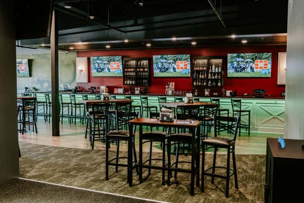 A larger space with lots of seating at the indoor golf restaurant