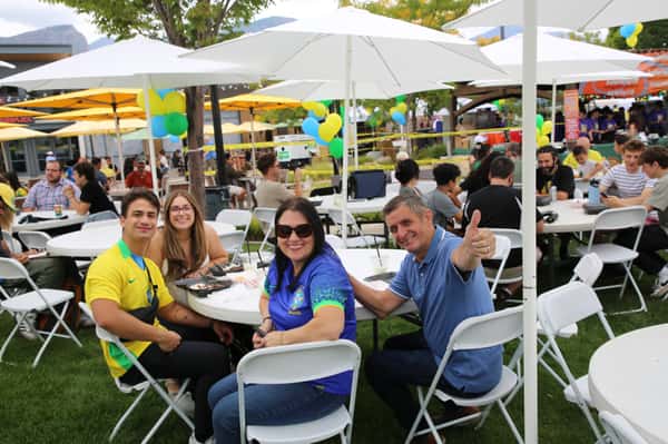 Group of attendees sitting at an umbrella table at community event