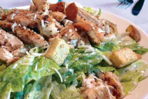 Lettuce salad with chicken and croutons, topped with shredded cheese