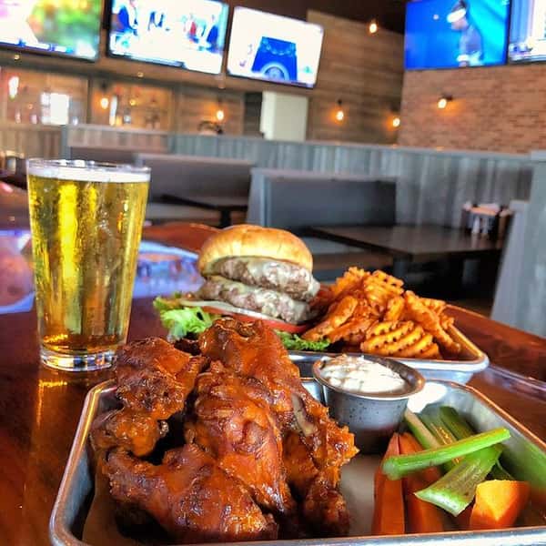 table with wings, a burger, and pint of beer