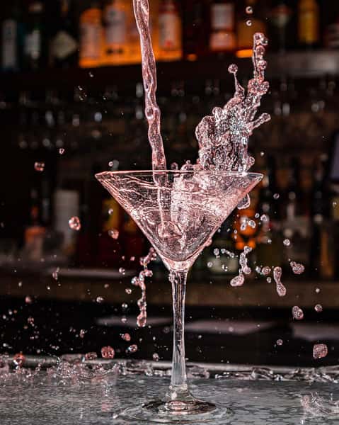 pouring cocktail into martini glass