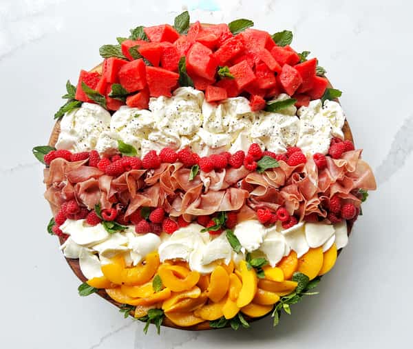 Fresh watermelon and tajin, fresh raspberries, fresh peaches drizzled with house infused hot honey, prosciutto, burrata, cracked black pepper, and mint