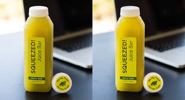 Bright yellow cold-pressed juice bottle with Squeezed branding, placed on a modern workspace background