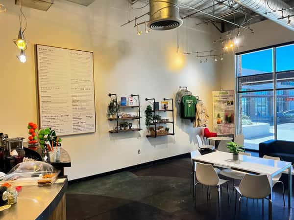 Bright juice bar prep station with menu board, fresh ingredients, and smoothie equipment in a minimalist, health-focused café setting