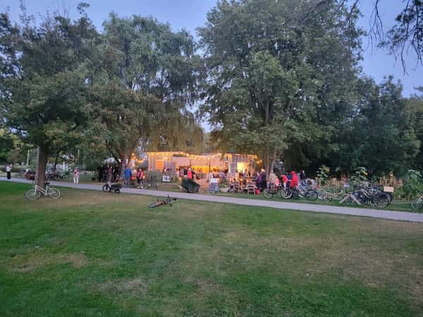 A twilight view of the outdoor food area with warm lights glowing from the blue kiosk.