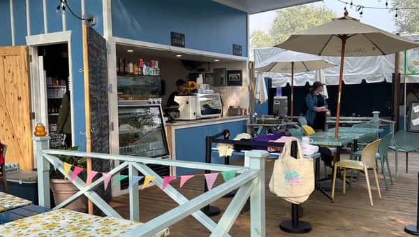 A view of the counter and service window of a blue outdoor food kiosk decorated with bunting.