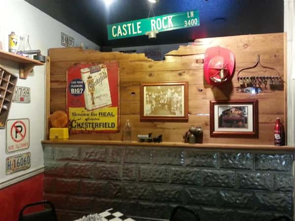 Wall with many vintage decorations and a street sign hanging overhead