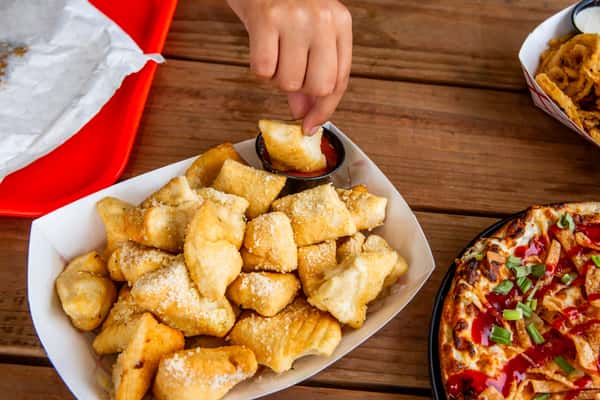 Parmesan puff bite being dipped in marinara at Jimmy's Burgers & Pizza