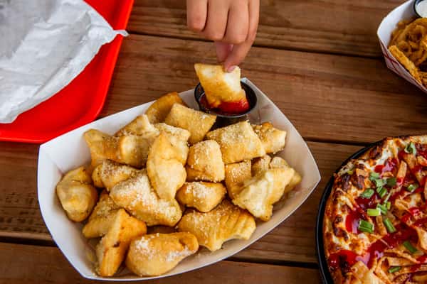 Parmesan puff bites being dipped in sauce at Jimmy's Burgers & Pizza in Hurst, TX