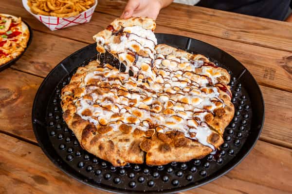 S'mores dessert pizza being finished with sweet drizzle at Jimmy's Burgers & Pizza