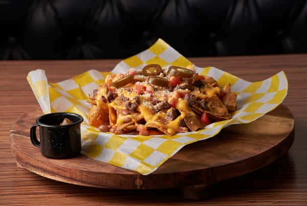 Loaded nachos topped with melted cheese, jalapeños and seasoned beef in a paper-lined basket