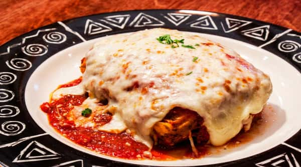 Classic Italian chicken parmesan topped with melted mozzarella and rich marinara sauce, served hot on a decorative plate at Tanino Ristorante Italiano fine dining restaurant.