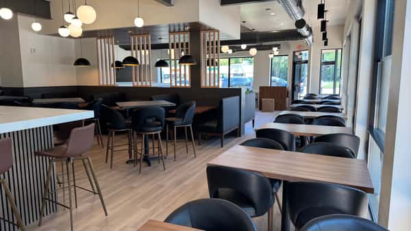 Dining area with dark upholstered chairs and wood tables near windows