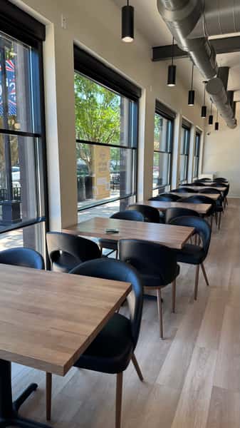 Dining area with round wood tables and black chairs beside windows