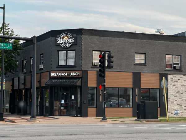 Exterior view of the Sunnyside Social storefront with brick and dark wood paneling