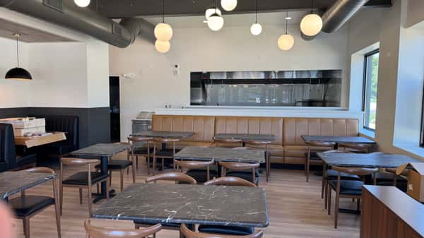 Restaurant interior with wooden bar, dining tables and chairs, and globe pendant lights hanging from the ceiling