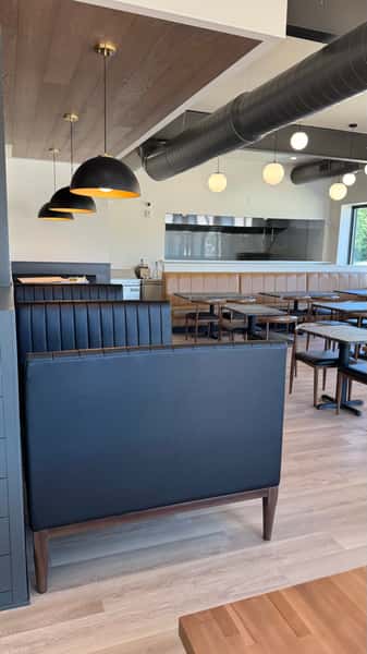 Restaurant bar counter with navy paneling and black dome pendant lights