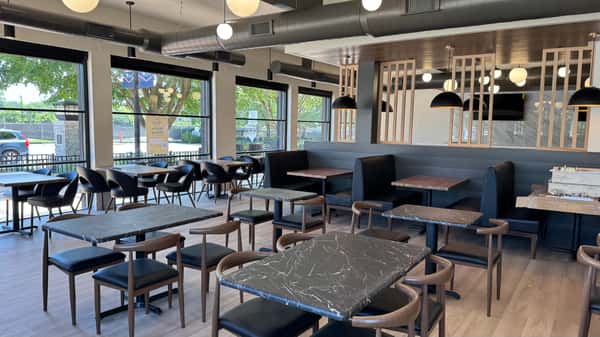 Dining area with black tables and booth seating next to large windows