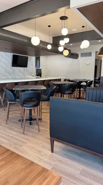 Dining area with high-top tables, wall-mounted TV, and blue booth seating