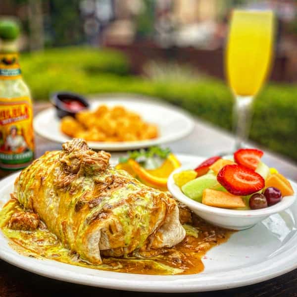 Saucy meal with a side of fruits and a drink