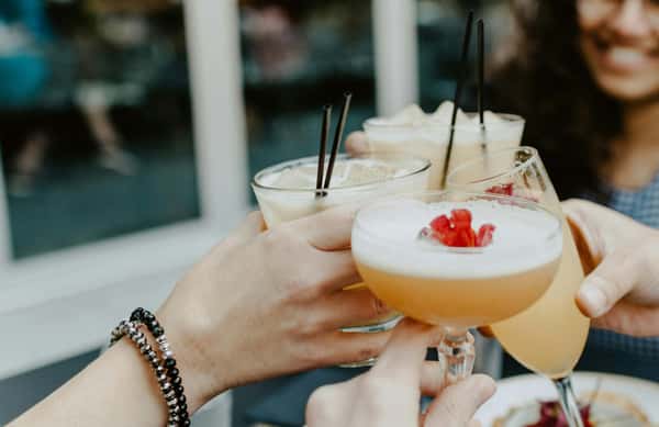 A group of four hands toasting cocktails