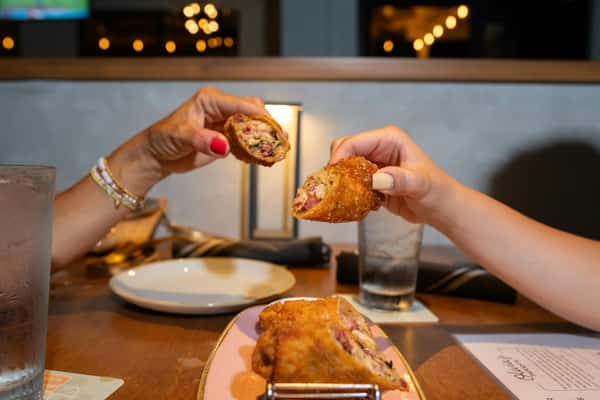 Two hands holding up egg rolls