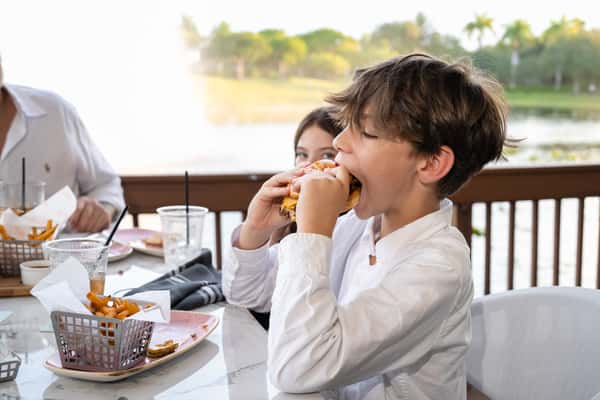 Young child taking a large bite from a burger