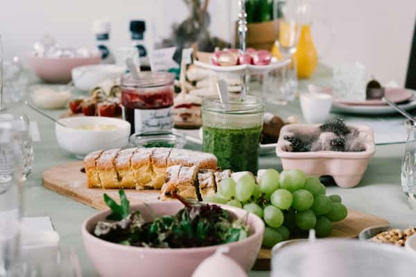 A table spread with a variety of drinks, fresh fruit, salads, bread, and jams