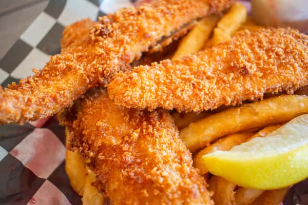 Golden, crispy breaded fish fillets served with a side of French fries and a lemon wedge.