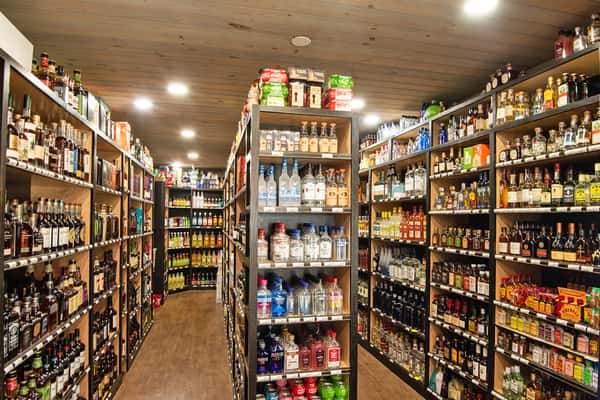 Interior view of a store aisle lined with shelves stocked with a wide variety of bottled beverages.