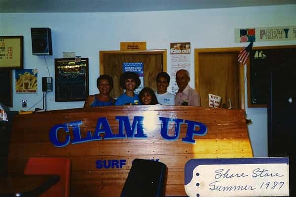five employees standing behind counter with words clam up